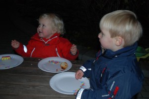 En glad lille pige og en dreng har spist deres æbleskiver